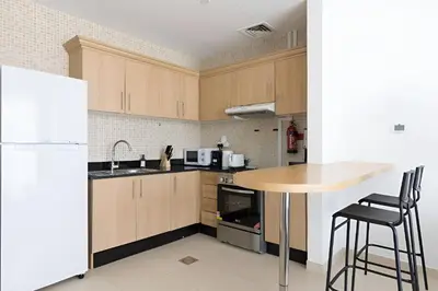 a kitchen with wooden cabinets and a table and a refrigerator at SkylineOasis1BR apt with BurjKhalifa & CanalView in Dubai