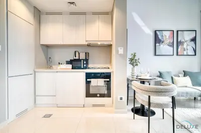 a kitchen and living room with a table and chairs at Canal Views! Promotional Rate on Lovely 1BR by Deluxe Holiday Homes in Dubai