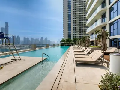 a swimming pool with chaise lounge chairs on a building at Marvelous 1BD Sea View Apartment with Beach Access in Dubai