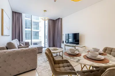 a living room with a table and chairs and a tv at District One I MBR I Spacious and Cozy in Dubai