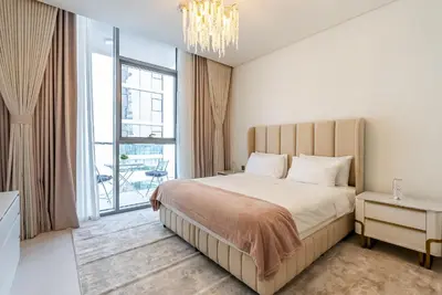 a bedroom with a large bed and a chandelier at District One I MBR I Spacious and Cozy in Dubai