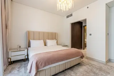 a bedroom with a large bed and a chandelier at District One I MBR I Spacious and Cozy in Dubai