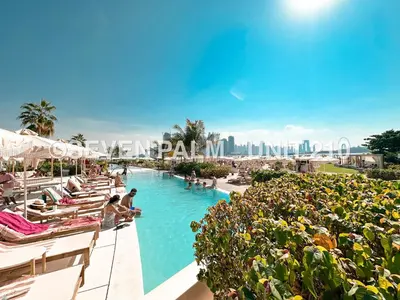 a pool at a resort with people sitting in chairs at Luxus-Studio mit Private Beach in Top-Lage, Meerblick & Infinity Pool! in Dubai