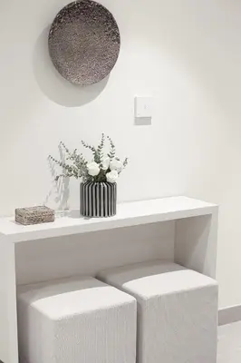 a white shelf with two stools and a vase with flowers at Forte Tower 1 - Fantastic Two Bedroom in Downtown Dubai in Dubai