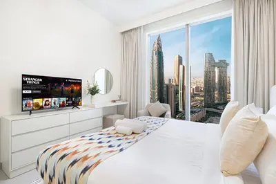 a white bedroom with a large window and a tv at Forte Tower 1 - Fantastic Two Bedroom in Downtown Dubai in Dubai