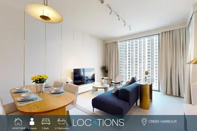 a living room with a blue couch and a table at Locations I Creek Harbor I Premium Modern 2BR I Luxury Interiors & Comfortable Stay I Close to Dubai Canal, Dining & Shopping I Pool, Gym & Parking in Dubai