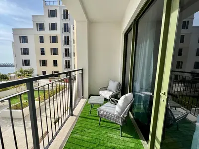 a balcony with a couch and chairs on a balcony at Brand New 2BR in La Rive with SeaView, Pool & Gym in Dubai