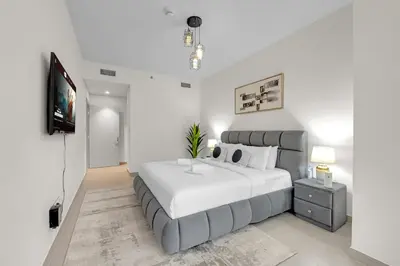 a white bedroom with a large bed and a tv at 2 BR in Forte, Close to Dubai Mall with Pool and Gym in Dubai
