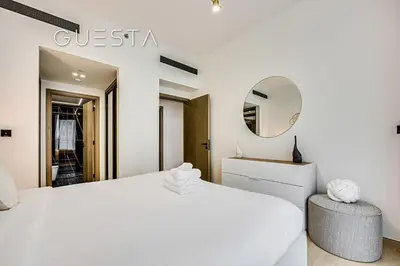 a white bedroom with a white bed and a mirror at Binghatti Crescent, Jumeirah Village Circle in Dubai