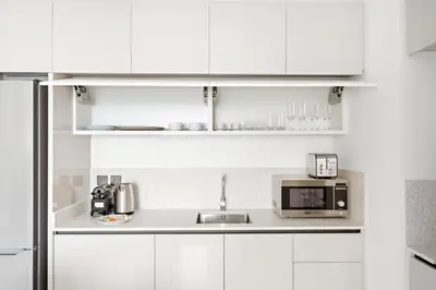 a white kitchen with a sink and a microwave at Silkhaus Sunset & Sea View in a Tower Private Beach in Dubai
