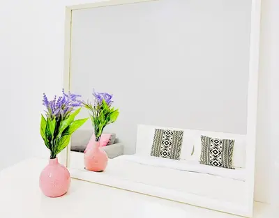 a mirror on a white shelf with pink vases at Studio Apartment in Dubai Marina with Balcony in Dubai