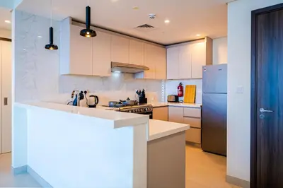 a kitchen with white cabinets and a counter top at Stylish 1BR in Wasl 1 with Balcony & Pool in Dubai