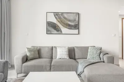 a living room with a gray couch and a table at Stylish 1BR in Wasl 1 with Balcony & Pool in Dubai
