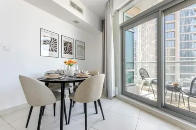 a dining room with a table and chairs and a window at Frank Porter - The Lofts West in Dubai