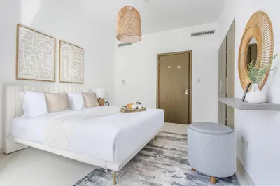 a white bedroom with a white bed and a blue stool at Frank Porter - The Lofts West in Dubai