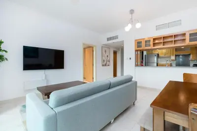 a living room with a blue couch and a kitchen at Lux BnB I Turia Tower I Lake & Garden View in Dubai