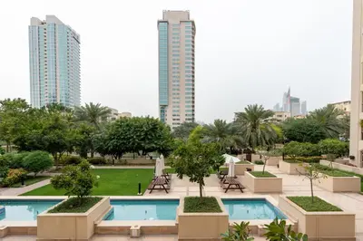 a resort with two pools and trees and buildings at Lux BnB I Turia Tower I Lake & Garden View in Dubai