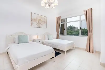 a white bedroom with two beds and a window at Lux BnB I Turia Tower I Lake & Garden View in Dubai