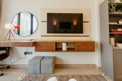 a living room with a tv and a mirror at Modern Oasis: Spacious Studio Near Dubai Downtown in Dubai
