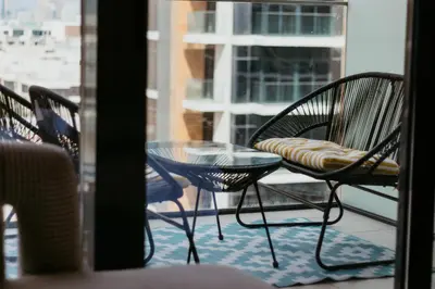 three chairs and a glass table on a balcony at Modern Oasis: Spacious Studio Near Dubai Downtown in Dubai