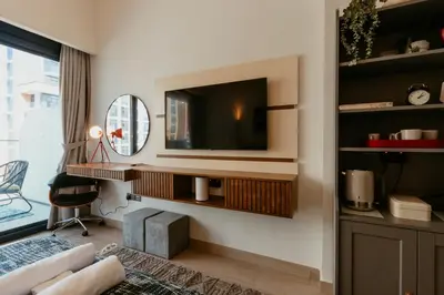 a living room with a tv on a wall at Modern Oasis: Spacious Studio Near Dubai Downtown in Dubai