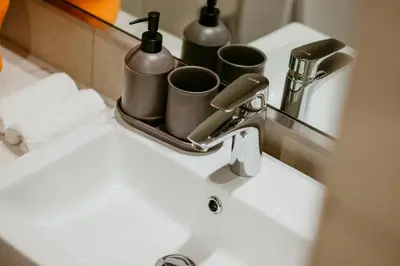 a bathroom sink with cups on top of it at Modern Oasis: Spacious Studio Near Dubai Downtown in Dubai