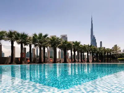 a swimming pool with palm trees and a tall building at Burj Daman, DIFC Dubai - Mint Stay in Dubai