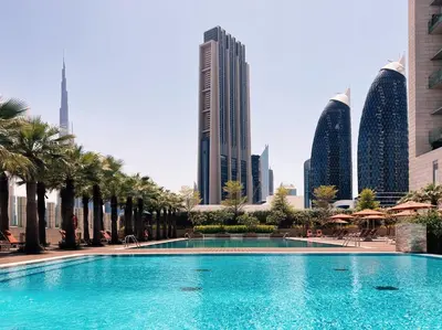 a large swimming pool with palm trees and buildings at Burj Daman, DIFC Dubai - Mint Stay in Dubai