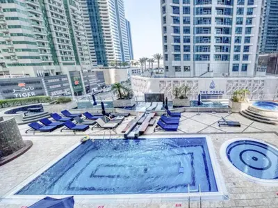 a swimming pool with blue lounge chairs and buildings at Stunning Marina View! CoLiving Rooms in Princess Tower Marina in Dubai