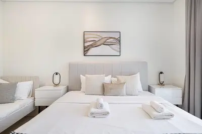 a white bedroom with two beds with towels on them at 2BR with Sea View & Terrace in Dubai