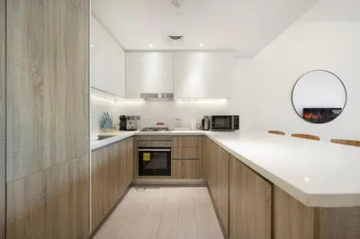 a kitchen with wooden cabinets and a white counter top at Sophisticated 1 Bed Suite in Dubai Marina in Dubai