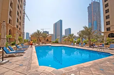 a swimming pool with lounge chairs and buildings at Upgraded 3BR Jacuzzi & Comfort at JBR in Dubai
