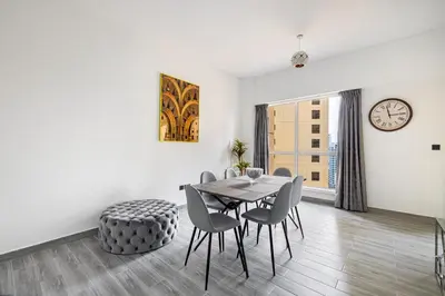 a dining room with a table and chairs and a clock at Upgraded 3BR Jacuzzi & Comfort at JBR in Dubai