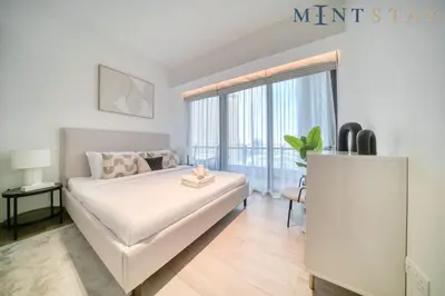a white bedroom with a bed and a large window at Silverene Tower B, Dubai Marina - Mint Stay in Dubai