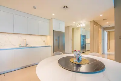 a white kitchen with a table and a sink at Privet Beach 2BR in Dubai Marina in Dubai