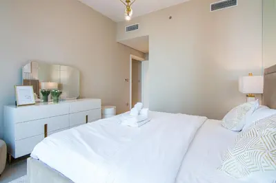 a white bedroom with a bed and a dresser at Privet Beach 2BR in Dubai Marina in Dubai