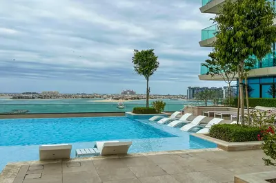 a swimming pool with lounge chairs and a building at Privet Beach 2BR in Dubai Marina in Dubai