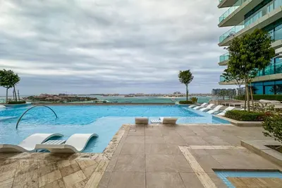 a swimming pool with white lounge chairs in a building at Privet Beach 2BR in Dubai Marina in Dubai