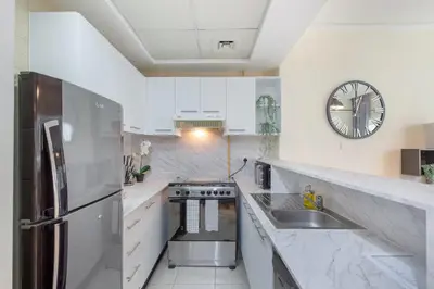 a kitchen with white appliances and a clock on the wall at HAVN - Studio in Downtown, Near Dubai Mall in Dubai
