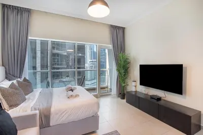 a living room with a tv and a bed and a couch at HAVN - Studio in Downtown, Near Dubai Mall in Dubai