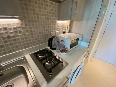 a small kitchen with a stove and a microwave at Black and white flower oasis in Seven Palm in Dubai