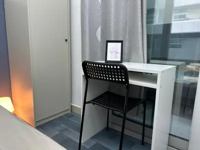 a white desk with a black chair next to a window at Partition Room 5 Mins to Mashreq Metro in Dubai
