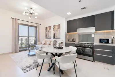 a kitchen and living room with a table and chairs at UrbanHomes - Exceptional 2 Bedroom Apt in A Family Friendly Neighborhood in Dubai