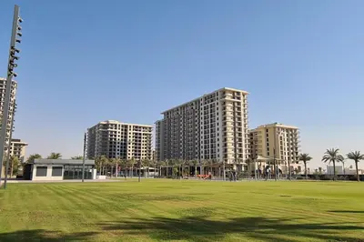 two tall buildings in a park with a green field at UrbanHomes - Exceptional 2 Bedroom Apt in A Family Friendly Neighborhood in Dubai