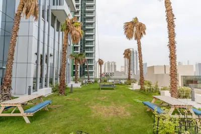 a park with benches and palm trees in front of a building at GuestReady Holiday Homes - Arabian Elegance in JVC in Dubai