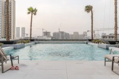 a swimming pool with palm trees in a city at GuestReady Holiday Homes - Arabian Elegance in JVC in Dubai