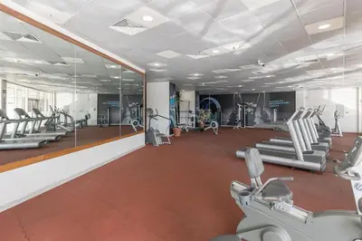 a gym with rows of tread machines and mirrors at HAVN -1 Bedroom Apartment with Dubai Marina View in Dubai