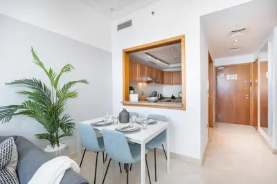 a dining room with a white table and blue chairs at HAVN -1 Bedroom Apartment with Dubai Marina View in Dubai