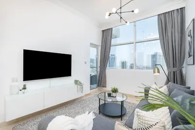 a living room with a tv on a white wall at HAVN -1 Bedroom Apartment with Dubai Marina View in Dubai
