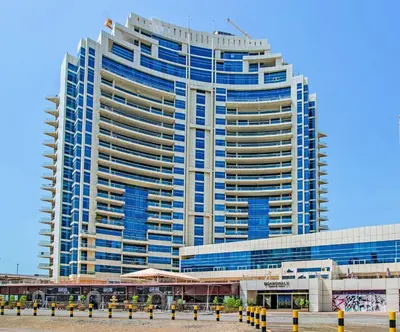 a tall building with blue windows in front of it at HAVN -1 Bedroom Apartment with Dubai Marina View in Dubai
